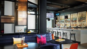 A modern bar area with a bar counter, seating, and a view of the city. - Aloft by Marriott Henderson (Henderson)