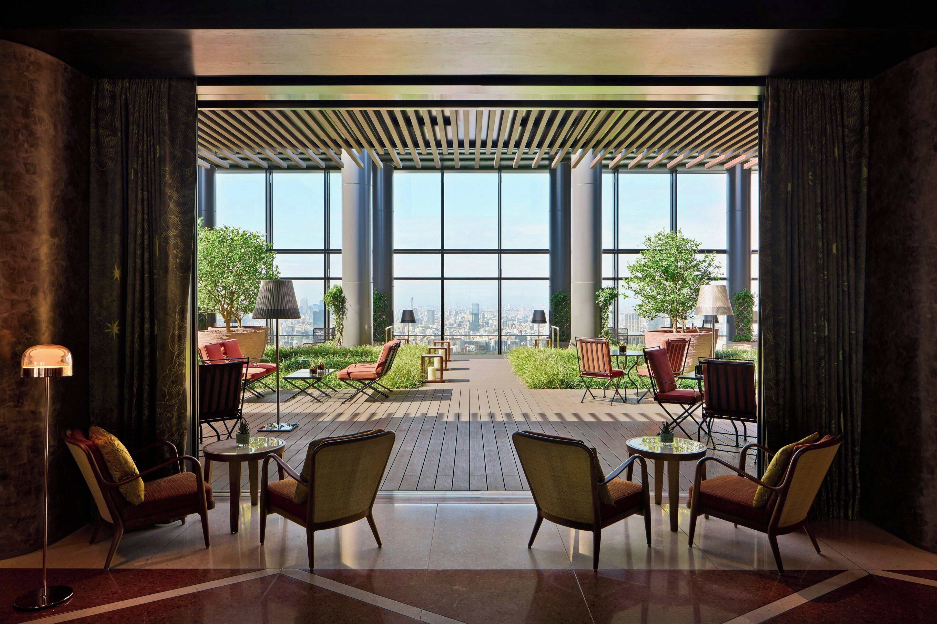A modern indoor patio with large windows, comfortable seating, and a city view.