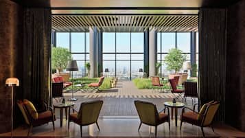 A modern indoor patio with large windows, comfortable seating, and a city view.