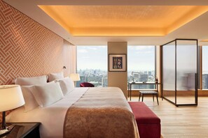 Habitación de hotel con una cama grande, un escritorio, una silla y vistas de la ciudad.