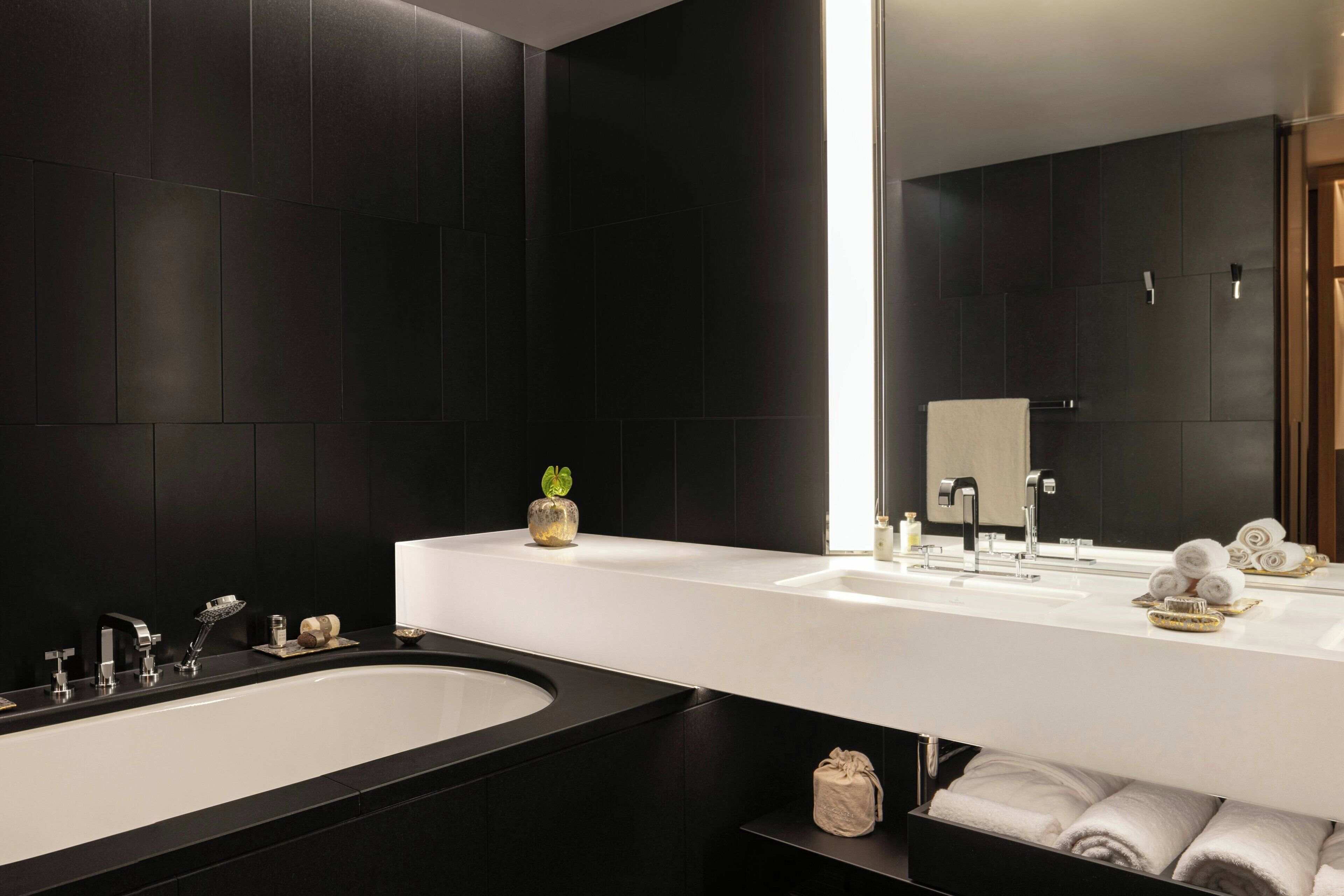 A modern bathroom with a large bathtub, two sinks, and a mirror.