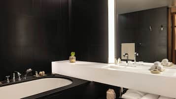 A modern bathroom with a large bathtub, two sinks, and a mirror.