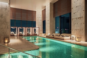 Un área de piscina interior moderna con asientos e iluminación.