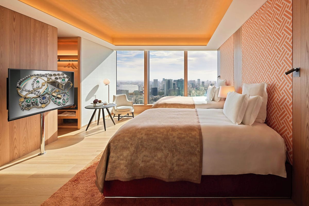 A modern hotel room with a large bed, a TV, and a city view.