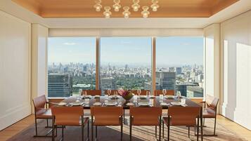 A dining room with a city view, large windows, and a modern chandelier.