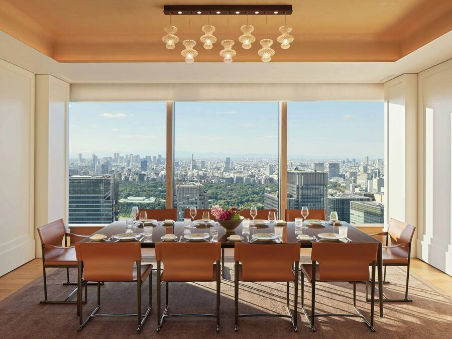 A dining room with a city view, large windows, and a modern chandelier.