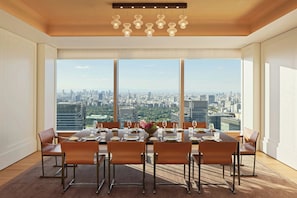 A dining room with a city view, large windows, and a modern chandelier.