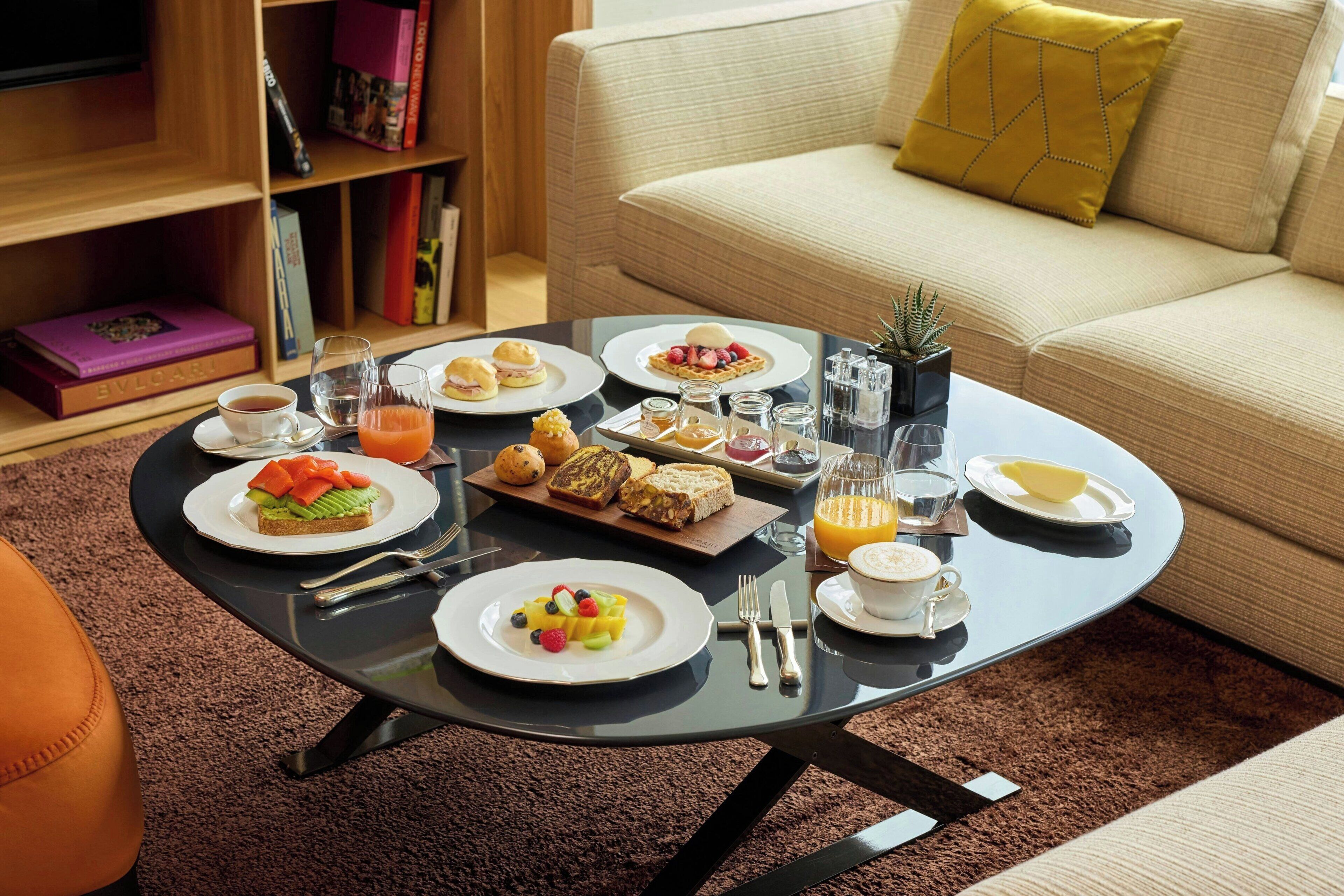 A breakfast setting with various dishes, a coffee cup, and a juice glass on a table.
