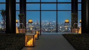 Eine moderne Hotelhalle mit Stadtblick durch große Fenster, mit einem durch Kerzen und Lampen beleuchteten Gang.