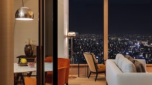 Ein modernes Wohnzimmer mit Stadtblick, ein Essbereich mit Tisch und Stühlen sowie ein großes Fenster.