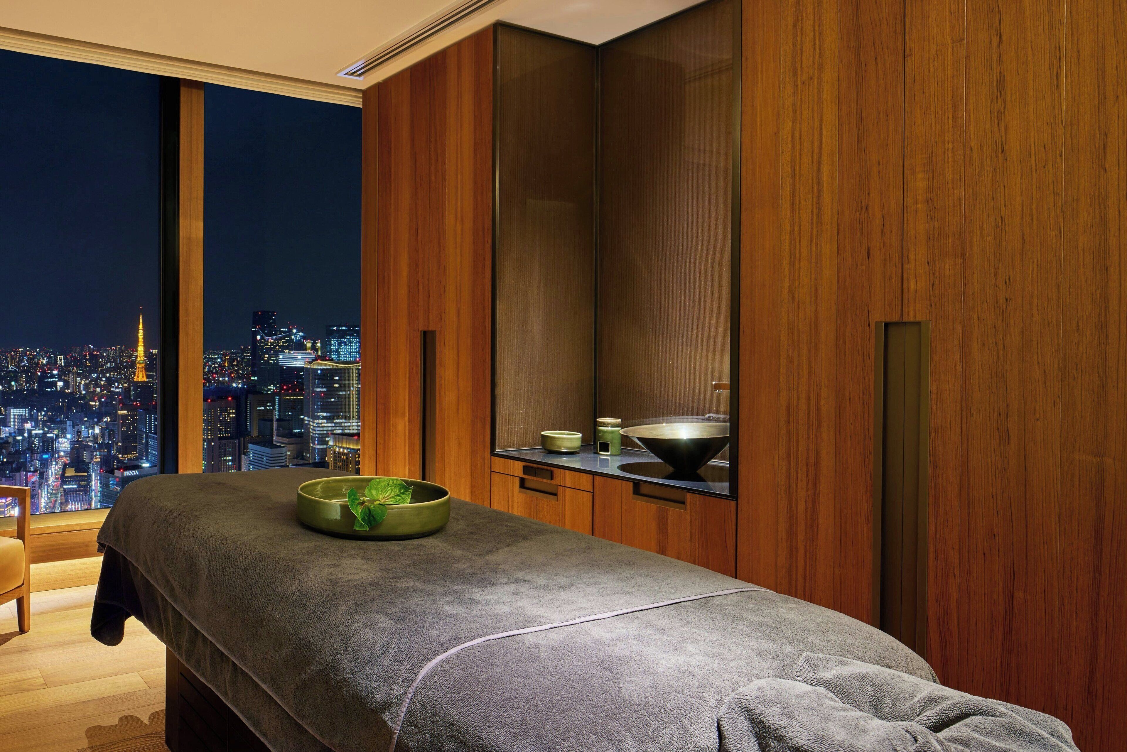 Ein modernes Zimmer mit Blick auf die Stadt, einer Massageliege und Holzschränken.