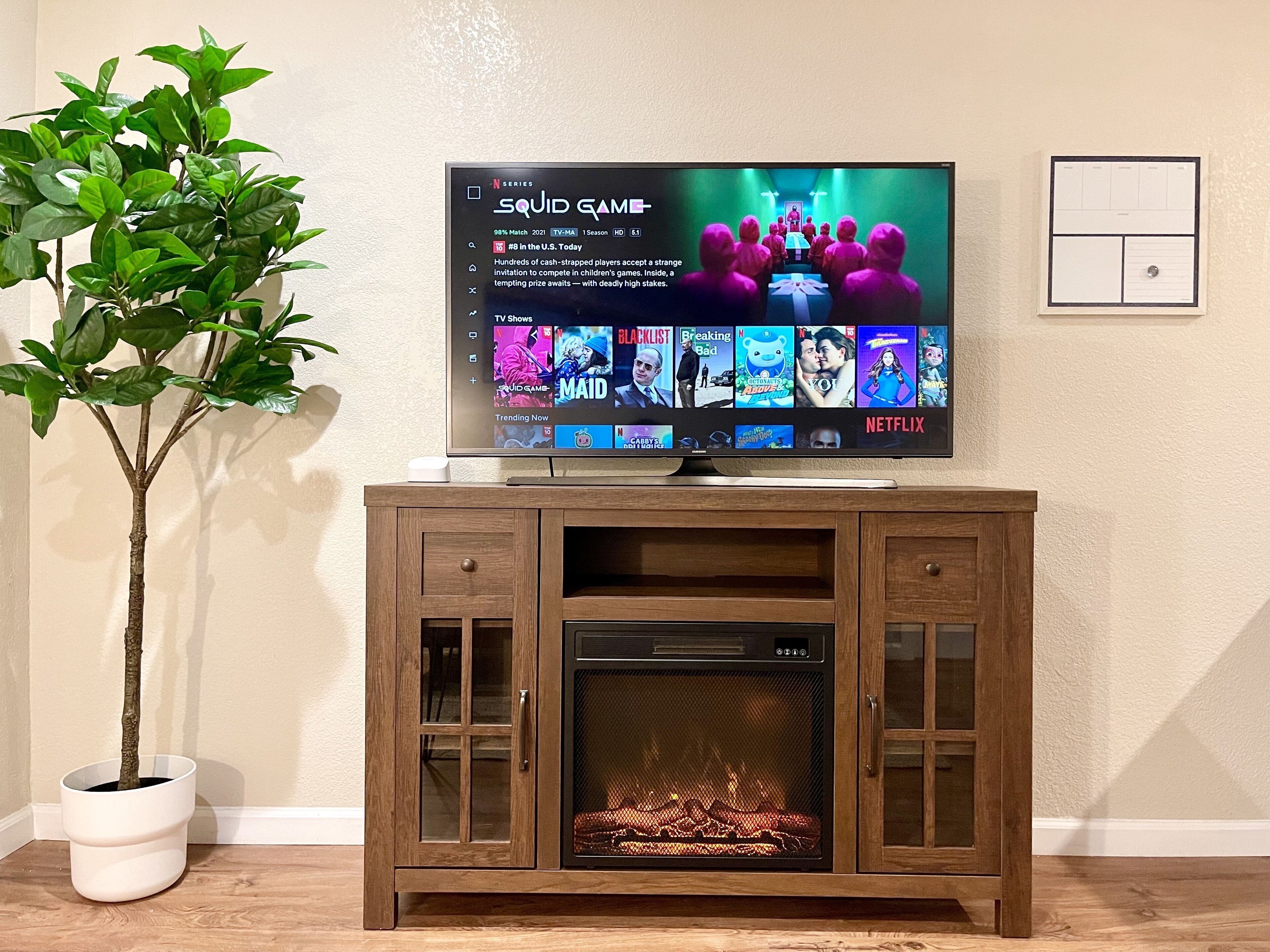 Ein Flachbildfernseher an einem Holzkabinett mit Kamin darunter.