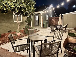 Eine Terrasse mit Gartenmöbeln, ein kleiner Garten und ein Baum mit gelben Früchten.