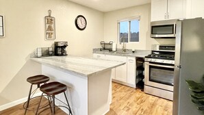 Una cocina moderna con una isla central, electrodomésticos de acero inoxidable y suelo de madera.