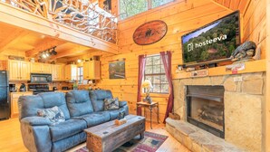 A cozy cabin interior with a wooden dining area, a fireplace, and a television displaying 'hosteeva'. - Bearway to Heaven #2 (Pigeon Forge)