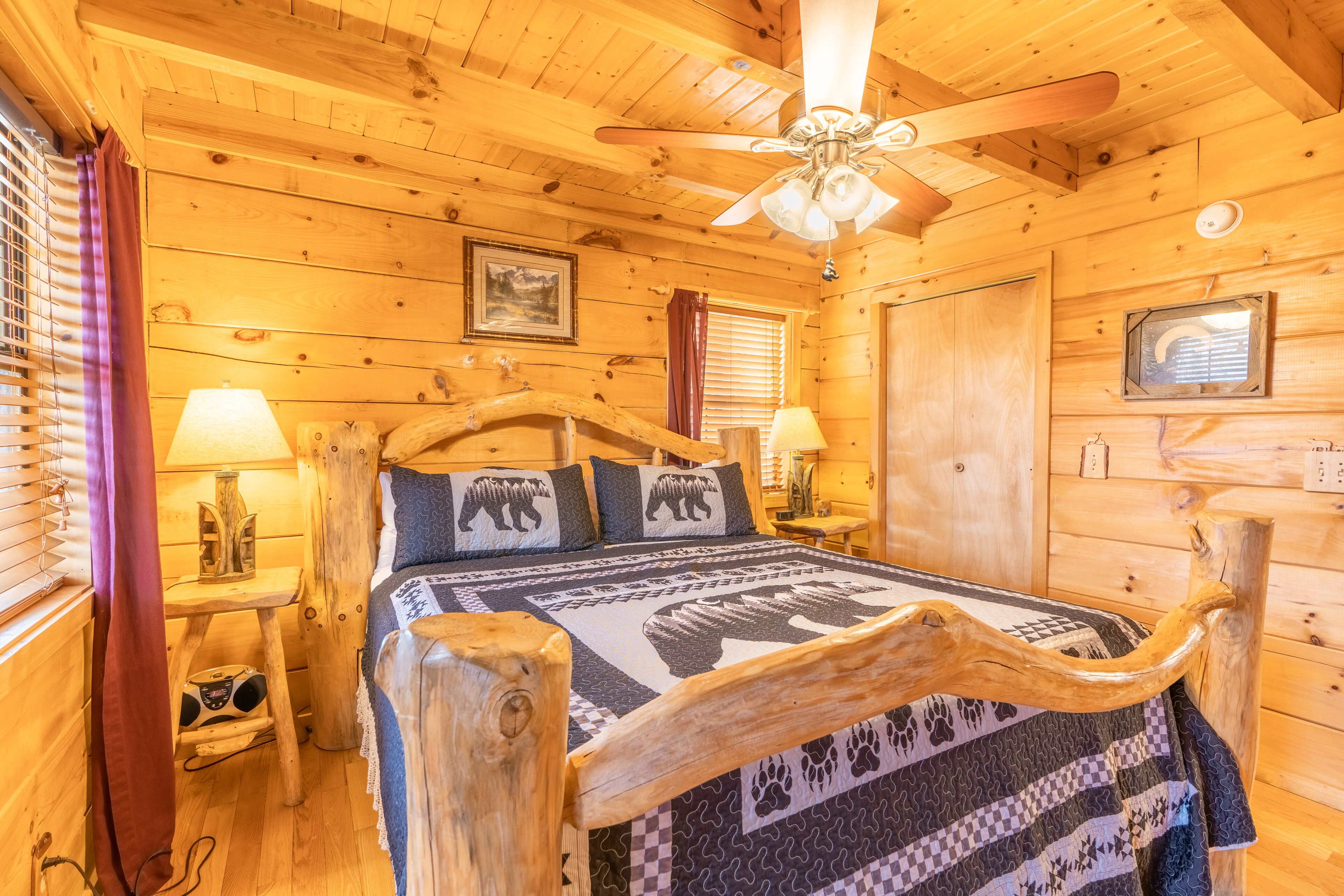 Une chambre dans une cabane en bois, avec un lit, un ventilateur de plafond et des murs en bois.