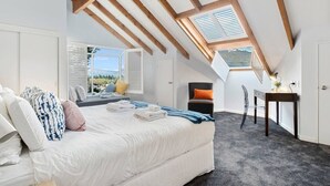 A bedroom with a skylight, a bed with pillows, a chair, a desk, and a view of the outdoors. - Stunning Views with a Fantastic Location! (Queenstown)