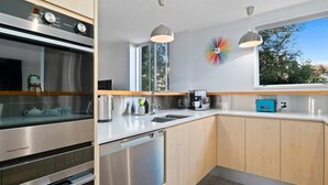 A modern kitchen with stainless steel appliances, wooden cabinets, and a large window providing natural light. - Stunning Views with a Fantastic Location! (Queenstown)