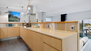 A modern kitchen with wooden cabinets, a stainless steel range hood, and pendant lighting. - Stunning Views with a Fantastic Location! (Queenstown)