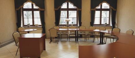 A conference room with a large table and chairs, large windows with curtains, and a reception desk.
