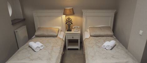 A twin room with two beds, a nightstand with a lamp, and a radiator.