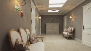Un couloir avec un canapé, des fauteuils, un meuble et une porte.