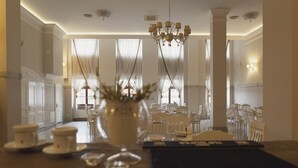 Un coin repas agrémenté d’un lustre, de chaises blanches et d’une table mise pour le repas.