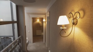 Un couloir avec une lampe fixée au mur et une rambarde.