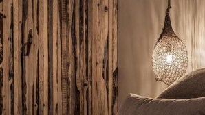 Un dormitorio con pared de madera, lámpara colgante con textura y una cama con almohadas.