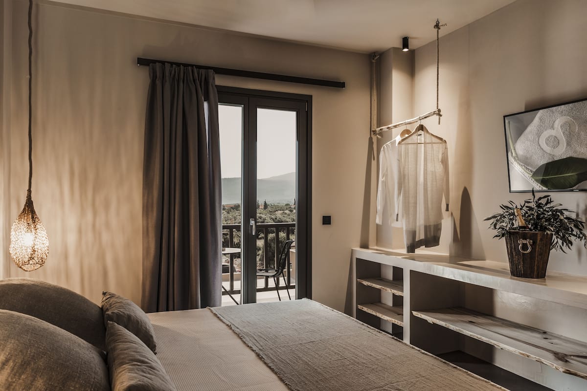 Une chambre avec un lit, un fauteuil suspendu, une télévision et un balcon avec vue.