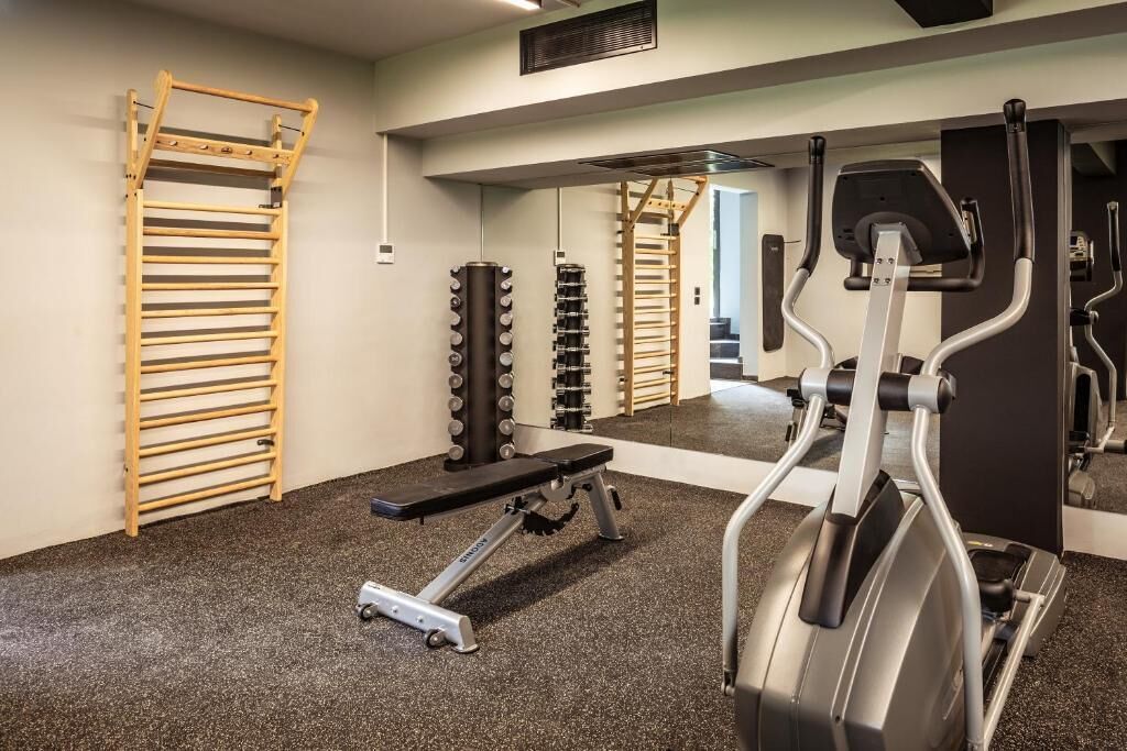 Una palestra con una panca per i pesi, un tapis roulant e un supporto a parete.
