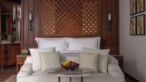 A hotel room with a bed, a round table with fruit, and a decorative wooden screen. - Anantara Ubud Bali Resort (Payangan)