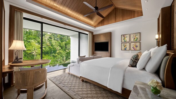 A spacious bedroom with a large bed, a ceiling fan, a TV, and a view of lush greenery. - Anantara Ubud Bali Resort (Payangan)
