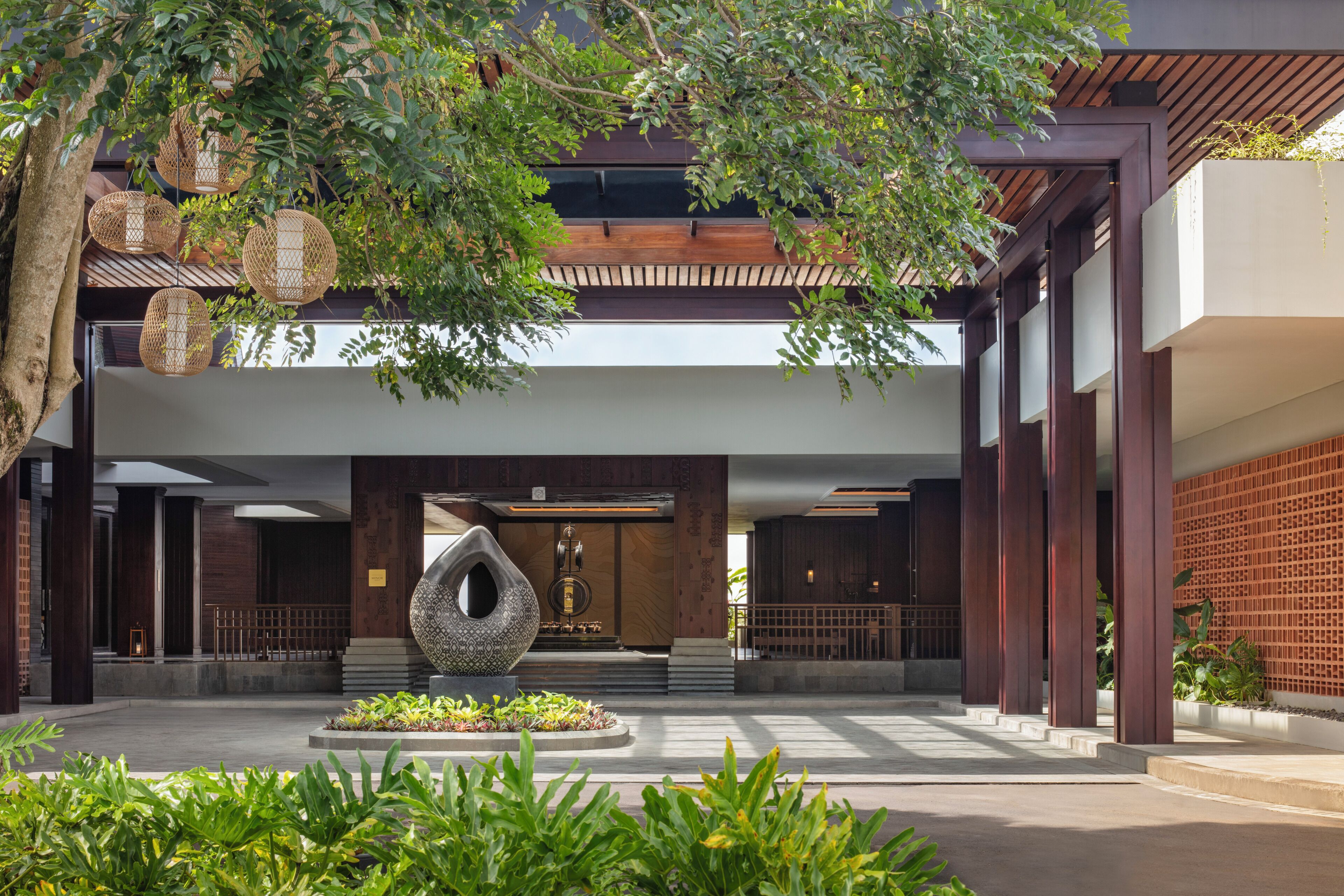 A modern building with a central atrium, a large decorative sculpture, and a well-maintained garden area.
