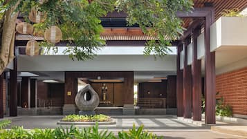 A modern building with a central atrium, a large decorative sculpture, and a well-maintained garden area.