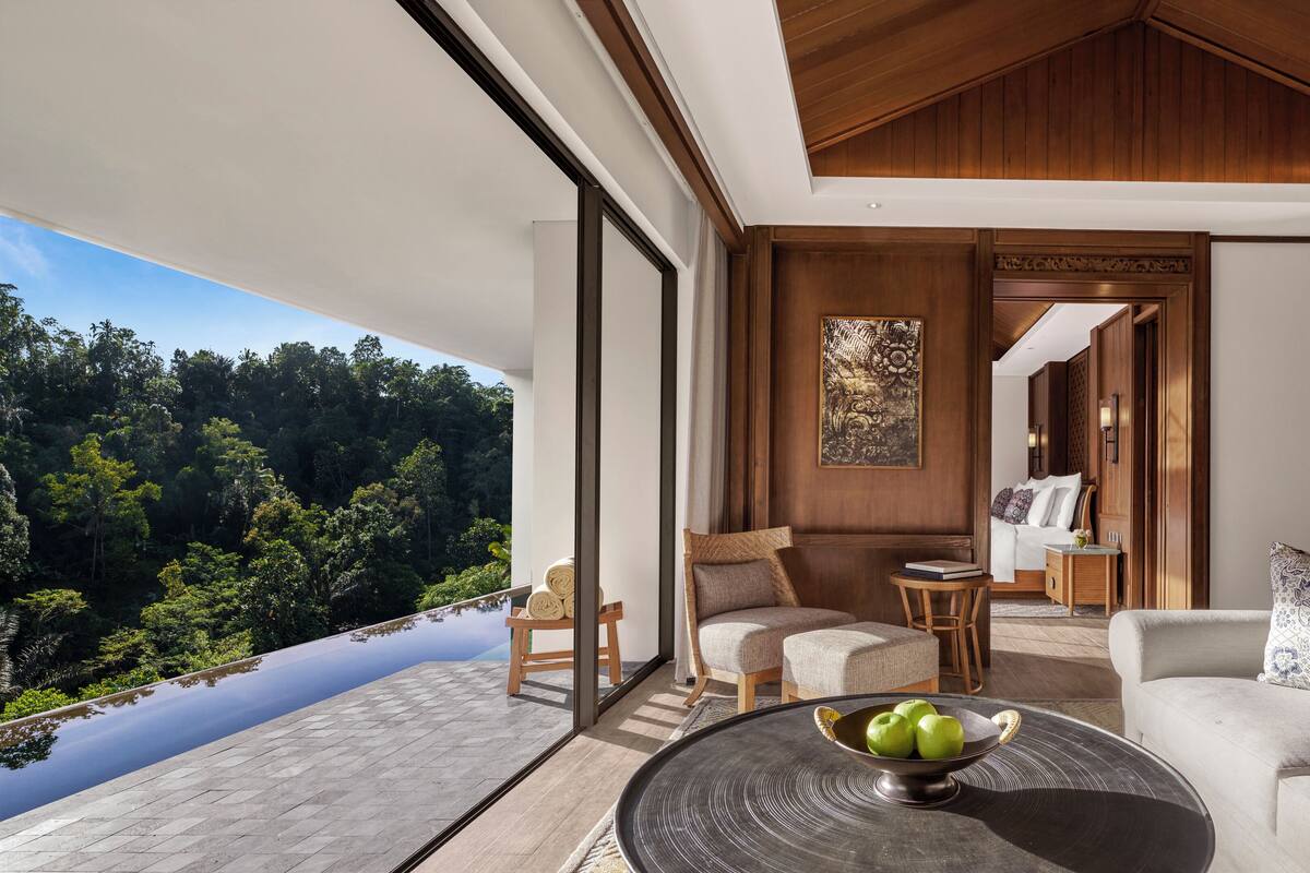 A modern room with a large window, a bed, a sofa, and a dining table.