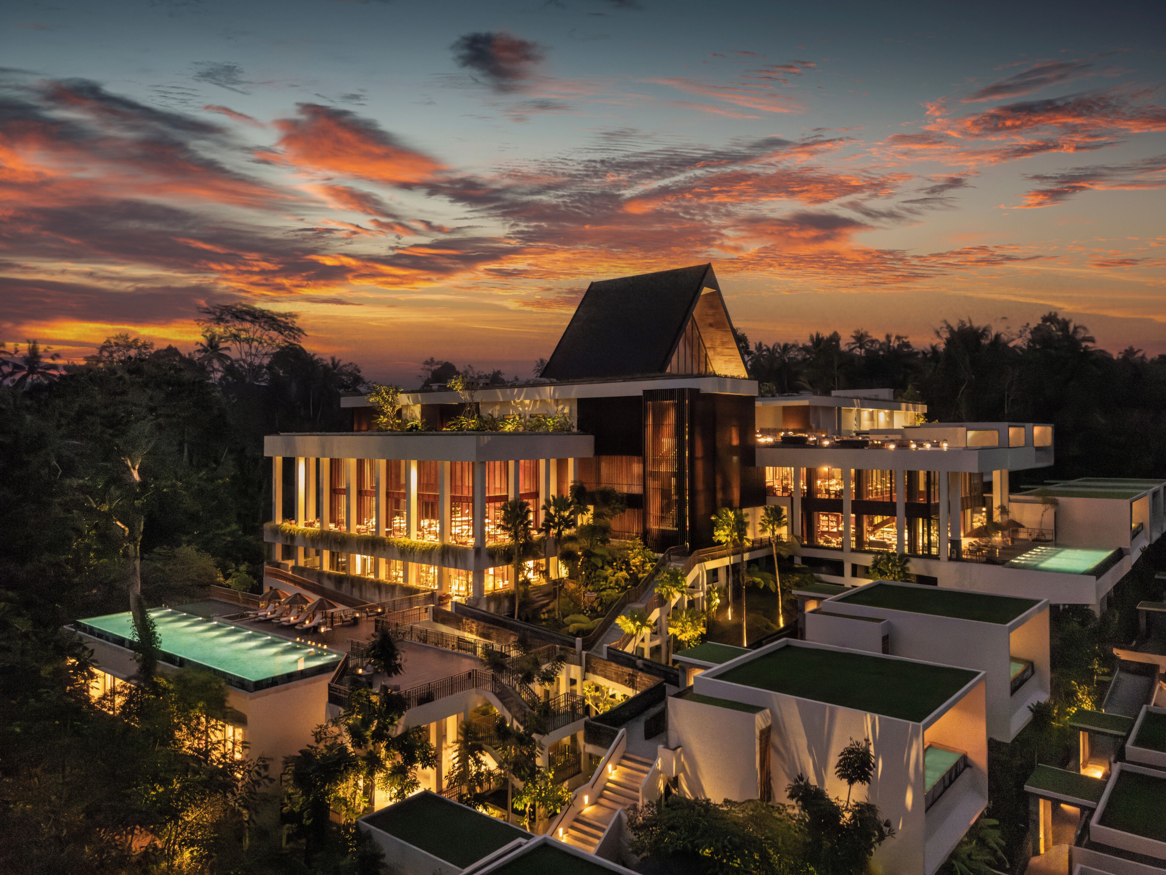 A modern resort with multiple buildings, interconnected walkways, and a pool area.