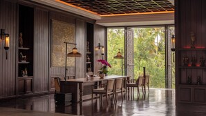 A spacious room with a wooden floor, a central dining table with chairs, a large window with a view of greenery, and decorative wall sconces. - Anantara Ubud Bali Resort (Payangan)