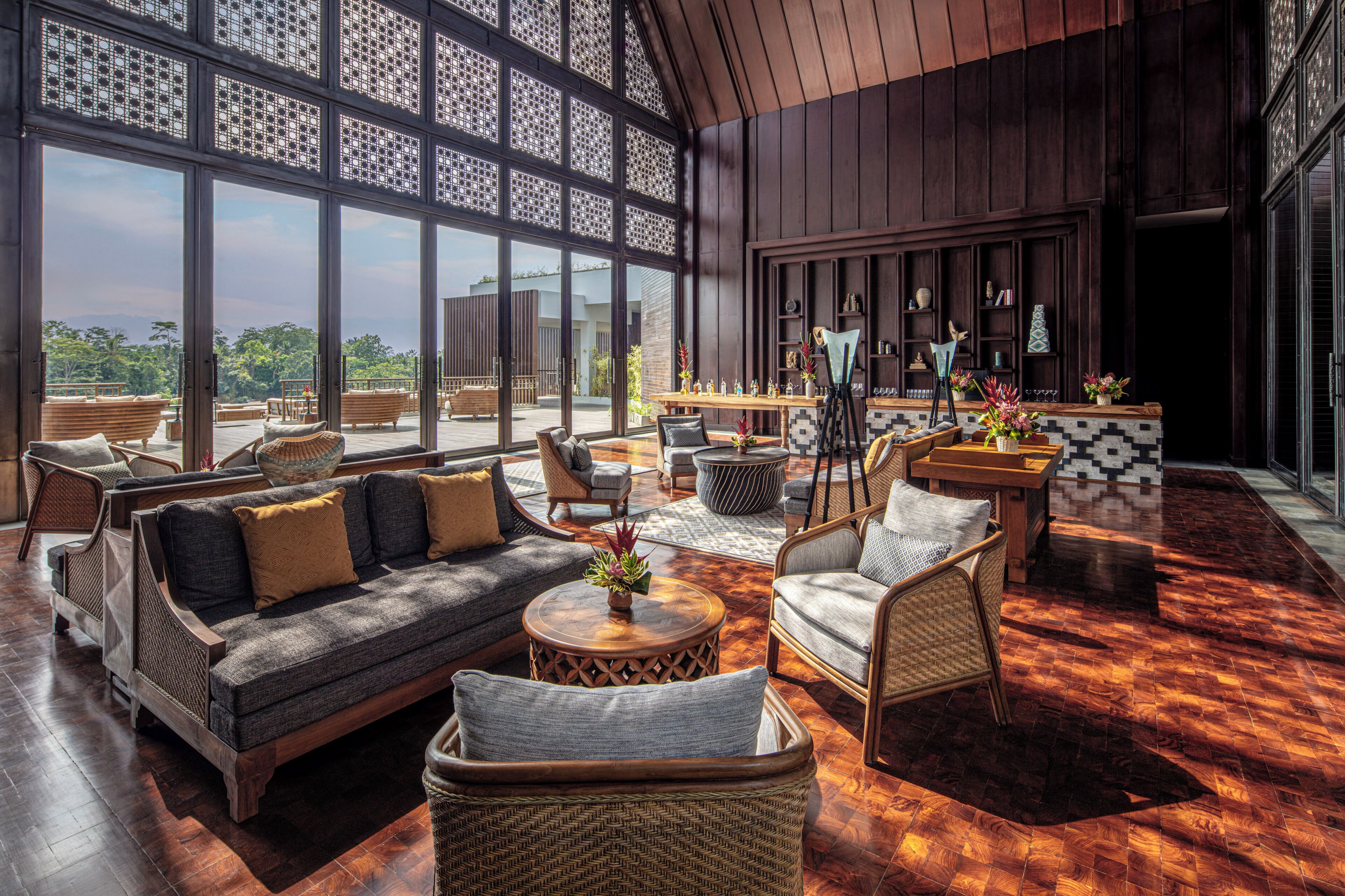 A spacious lounge area with a large wooden table, comfortable seating, and a view through large windows.