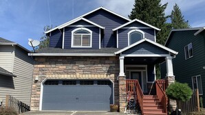 A two-story house with a stone facade, a large garage, and a front porch with a staircase. - Beautiful house near Columbia Gorge (Gresham)