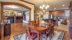 A spacious dining area with a wooden table and chairs, a chandelier, and a kitchen in the background. - Beautiful house near Columbia Gorge (Gresham)
