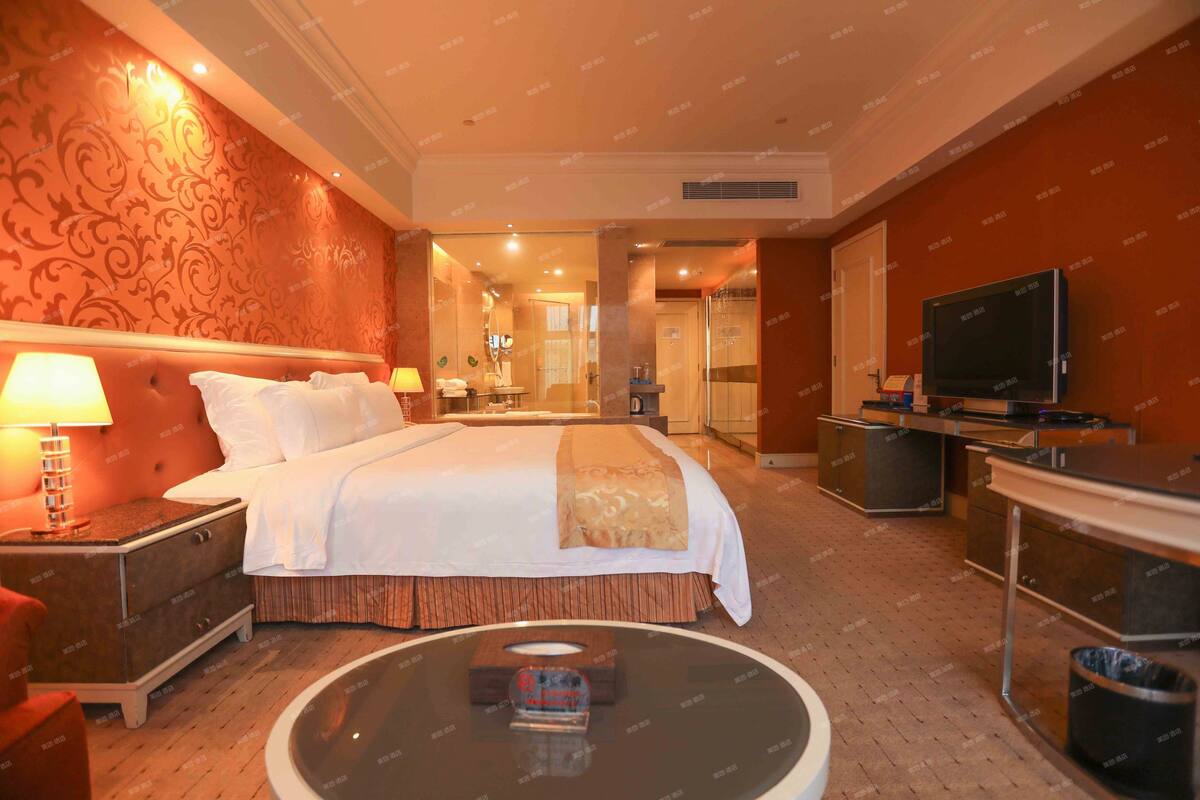 A hotel room with a large bed, a TV, a desk, and a coffee machine.