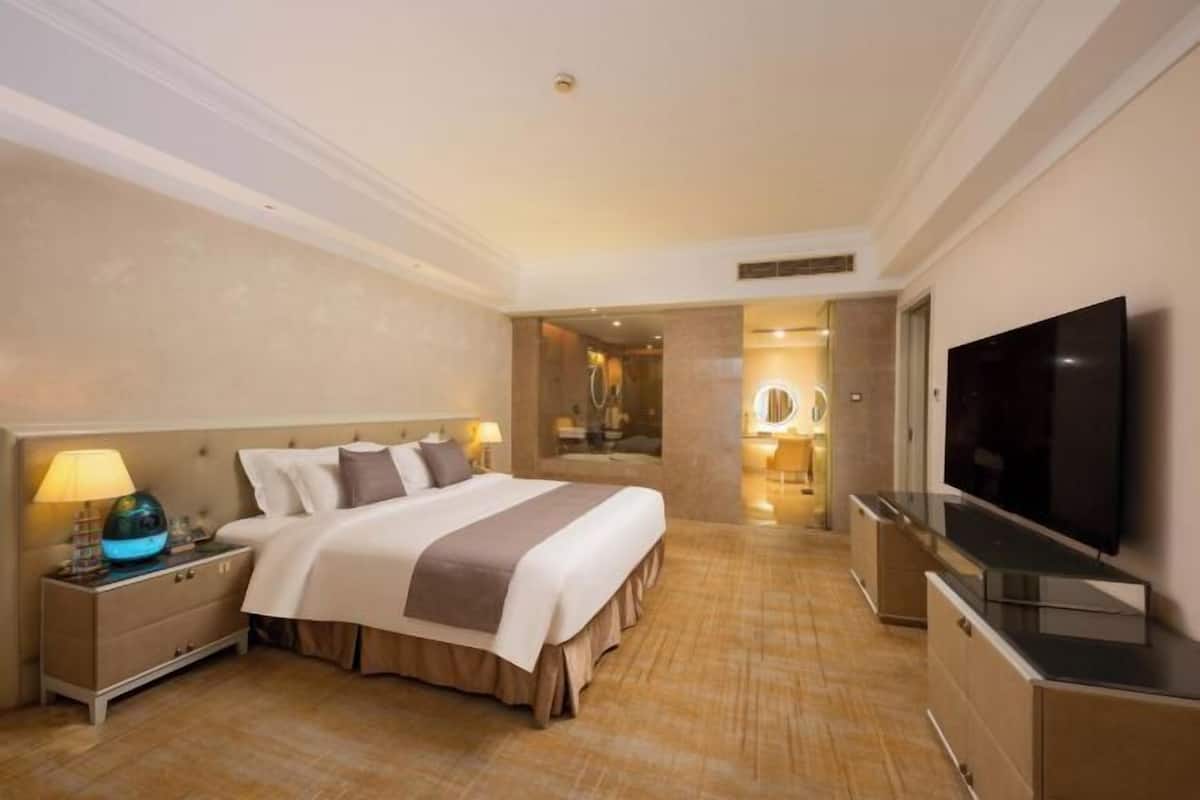 A hotel room with a bed, a TV, a nightstand, and a mirror.