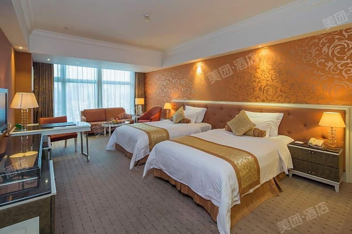 A hotel room with two beds, a sofa, a desk, and a minibar.