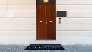 A wooden door with a metal grill, a doormat with "CIVITALoft Luxury Apartment" text, and a small plaque on the wall. - Civitaloft (Civitanova Marche)