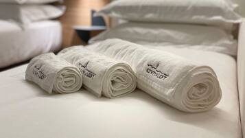 A neatly made bed with rolled white towels and a wooden headboard.