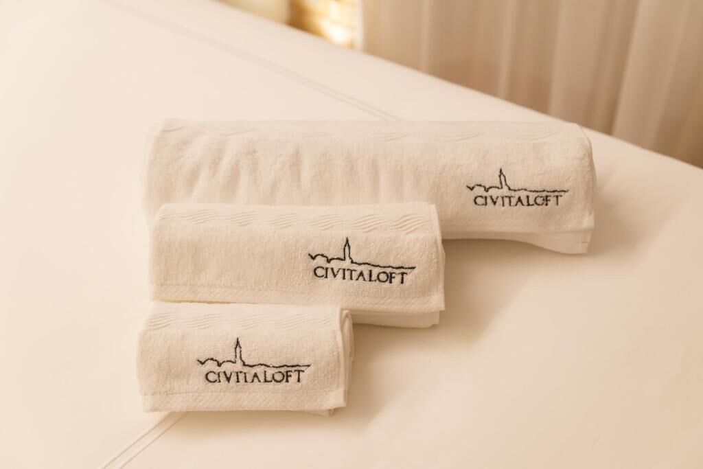 Tre asciugamani piegati ordinatamente con il logo 'CIVITALOFT' su una superficie bianca.
