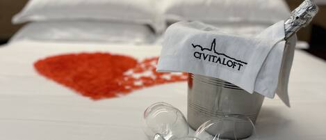 Una cama con sábana blanca, un balde con etiqueta y una mancha con forma de corazón.