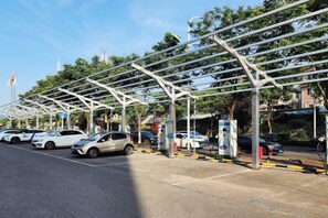 Una zona de estacionamiento techada con varios autos, un quiosco y una bandera.