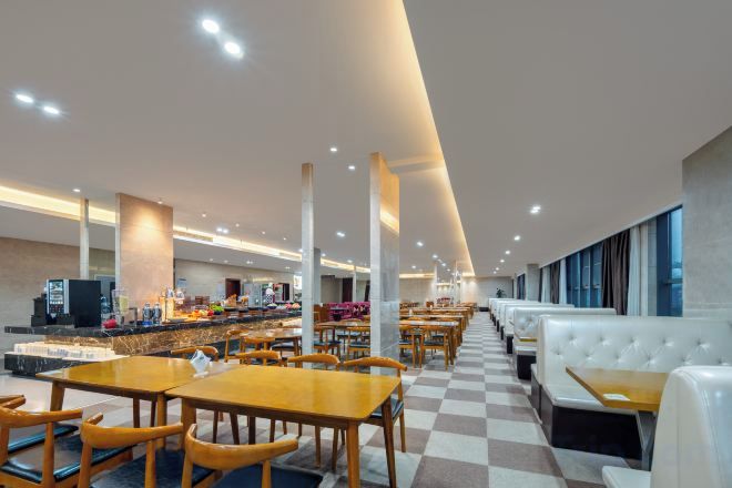 A modern restaurant with checkered flooring, wooden tables, and white cushioned booths.